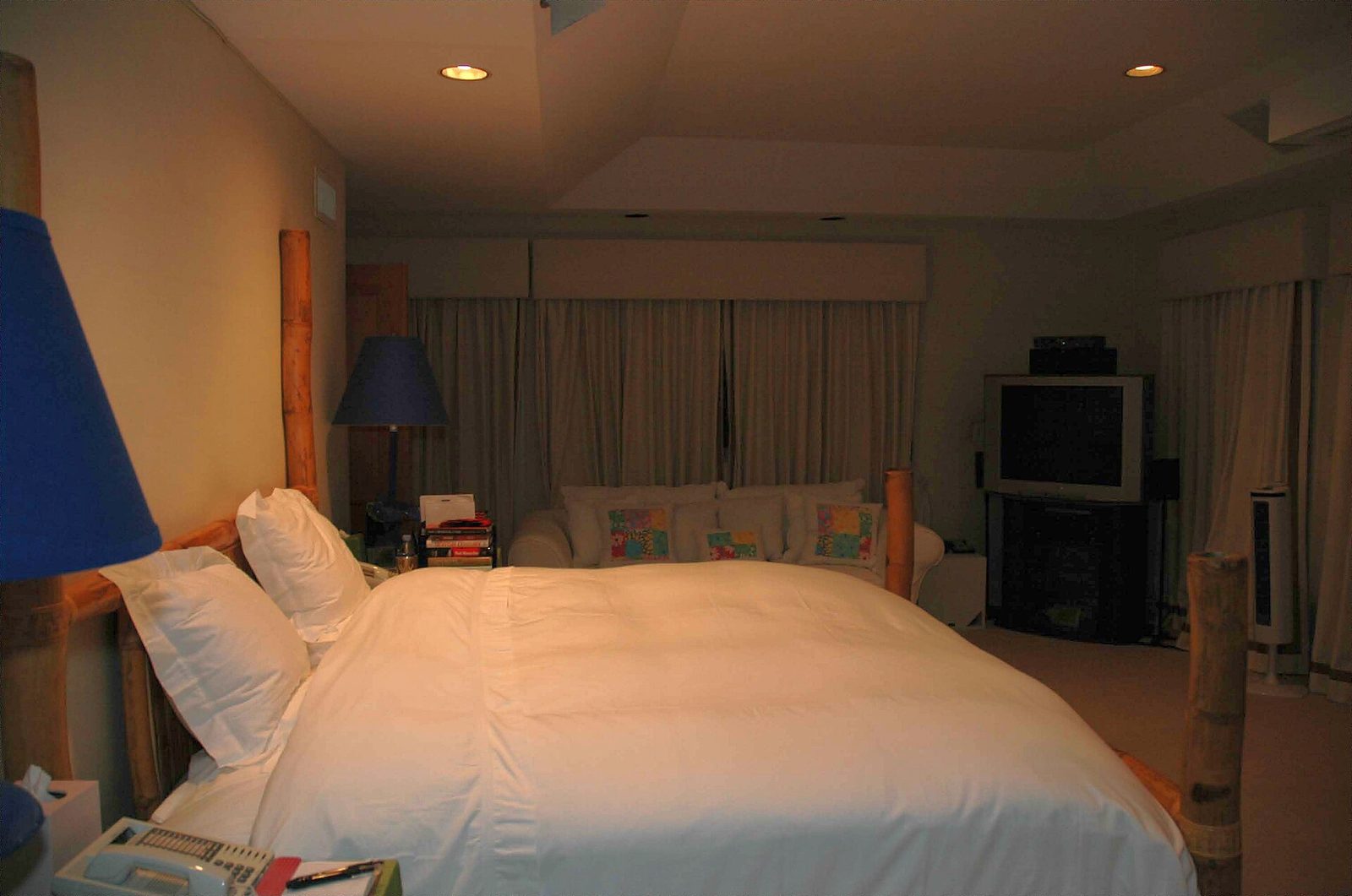 Room with a double bed in pale linen and warm lighting